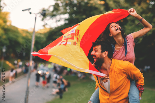  Young couple dancing at a festival with a Spanish national flag
