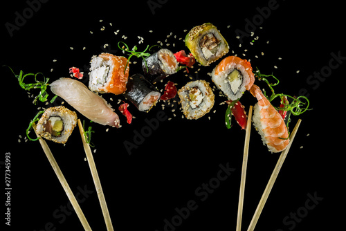 Seamless pattern with sushi. Food abstract background. Flying sushi, sashimi and rolls isolated on the black background.
