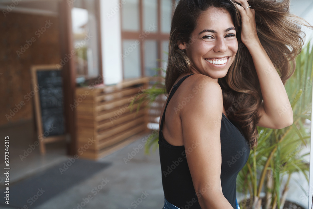 Lovely carefree tanned girlfriend in white tank-top laughing coquettish smile camera put hand through hair flirting having fun boyfriend funny sense humour, joking, standing cafe terrace