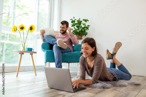 Couple reading newspapers and using laptop computer