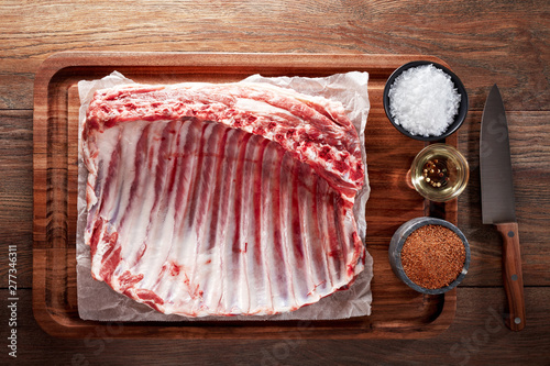 Raw rack of lamb ribs on white cooking paper and wooden cutting table photo