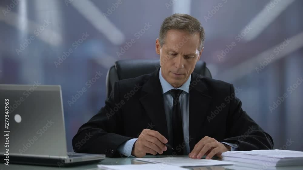 Attentive male director signing documents at office desk, kind employer, work Attentive male director signing documents at office desk, kind employer, work