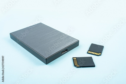 Mobile hard drive and memory card on blue background