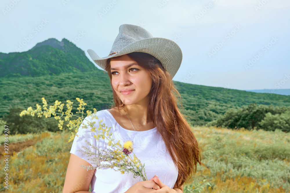 Girl in cowboy dress standing back on the top of Caucasus mountain.