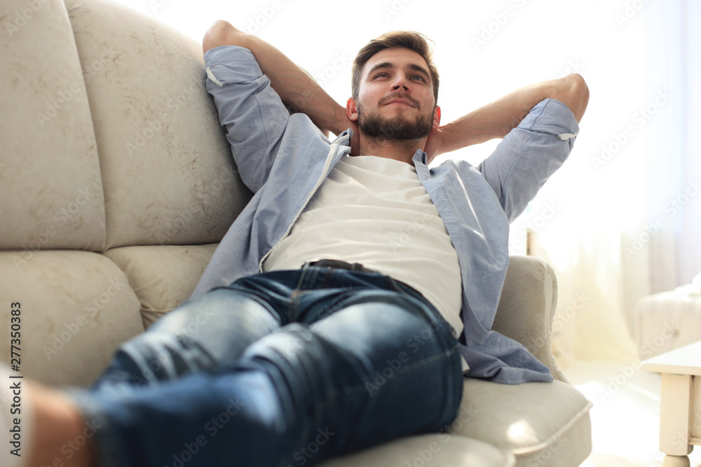 Portrait of a casual tired man resting sitting on a couch at home.