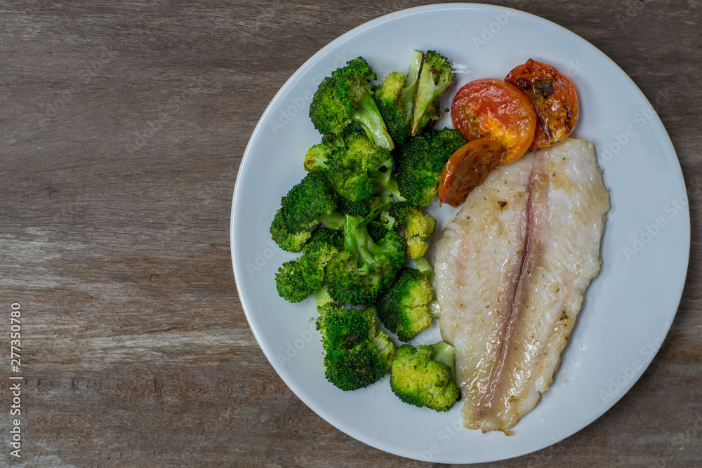Grilled Fish Fillet with tomato and broccoli vegetables on wood background homemade. Grilled Fish Fillet with tomato and broccoli vegetables on wood background homemade.