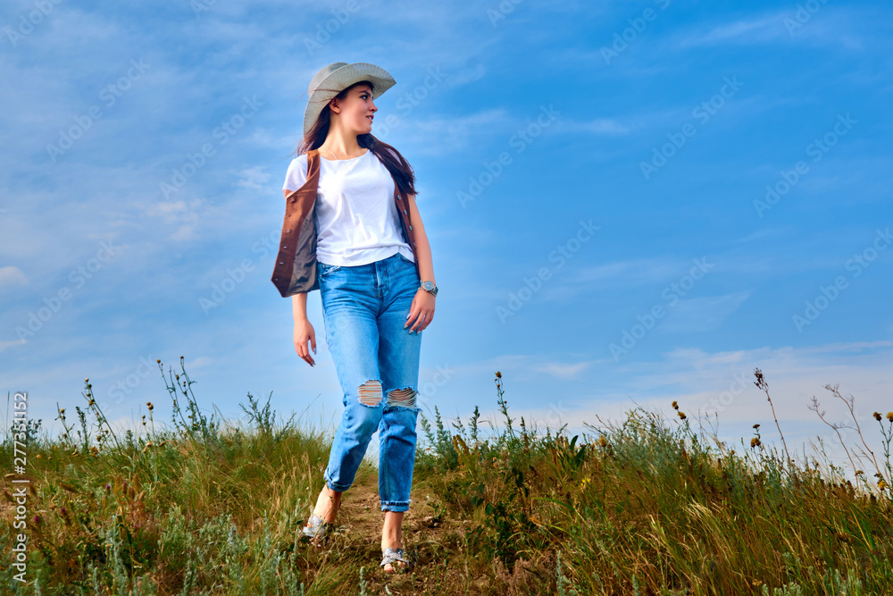 Girl in cowboy dress standing back on the top of Caucasus mountain with a scenery view to sunset at green valley. Female travel nature concept. Girl in cowboy dress standing back on the top of Caucasus mountain with a scenery view to sunset at green valley. Female travel nature concept.