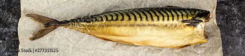 Banner of Smoked mackerel without head on baking paper on black background