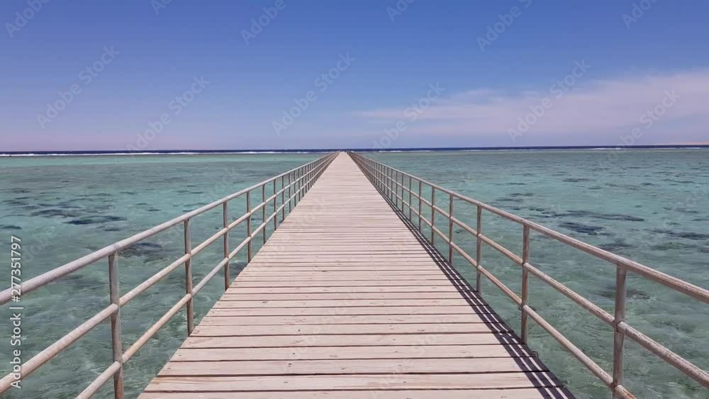 Perspective view of a wooden pier in the sea, against a clear blue sky Perspective view of a wooden pier in the sea, against a clear blue sky