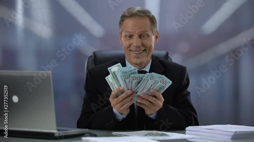 Greedy businessman holding bunch of dollars, rejoicing easy income, high salary