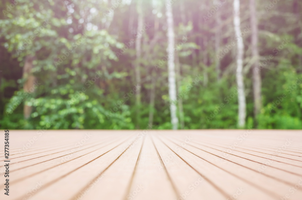 Summer forest background - in the foreground a wooden surface, in the background - a blurred forest. Place to insert items, text, logo. Minimalism. Summer forest background - in the foreground a wooden surface, in the background - a blurred forest. Place to insert items, text, logo. Minimalism.