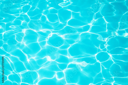 Bright blue water in the pool with a sun glare. Background image  water texture. The concept of swimming in the pool  recreation. Place for text.