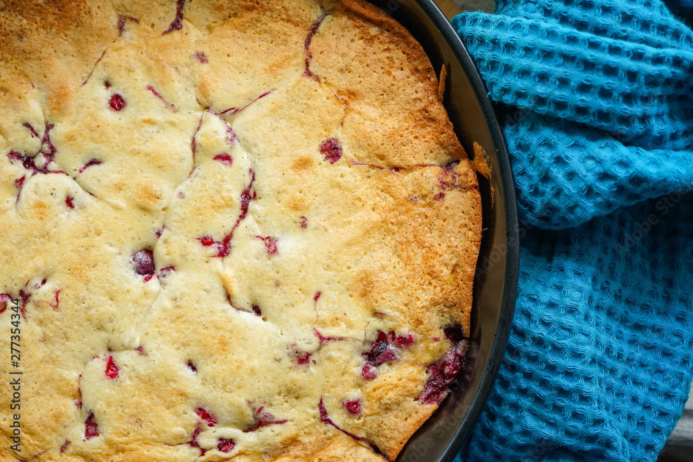 freshly baked cherry pie in a baking dish with a beautiful crafting blue towel