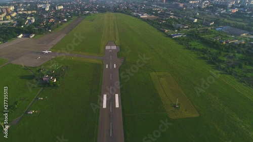 Slow motion of passenger airliner moving along take off runaway at dusk, city airport, gains height. 4K.