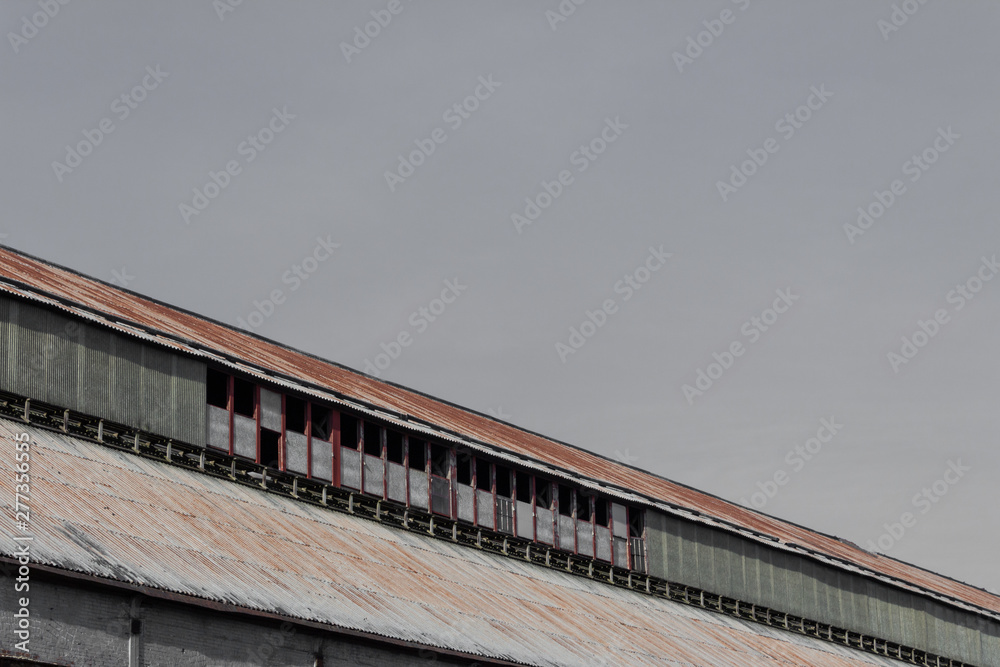 Angled view of industrial rooftop against a gray sky, corrugated metal, copy space, horizontal aspect