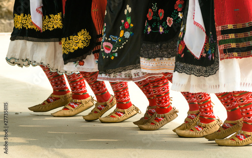 Girls dancing folk dance. People in traditional costumes dance Bulgarian folk dances. Close-up of female legs with traditional shoes, socks and costumes for folk dances.