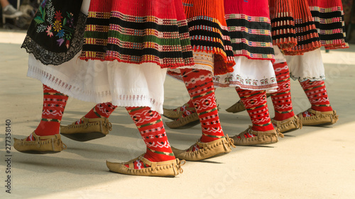 Girls dancing folk dance. People in traditional costumes dance Bulgarian folk dances. Close-up of female legs with traditional shoes, socks and costumes for folk dances.