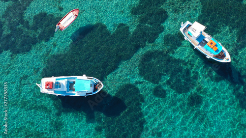 Aerial drone top view photo of traditional colourful fishing boat near iconic beach of Ornos with emerald clear sea, Mykonos island, Cyclades, Greece © aerial-drone