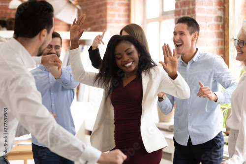 Happy funny black businesswoman with diverse team enjoy victory dance