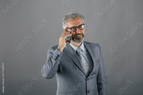 senior businessman using cellphone on gray background