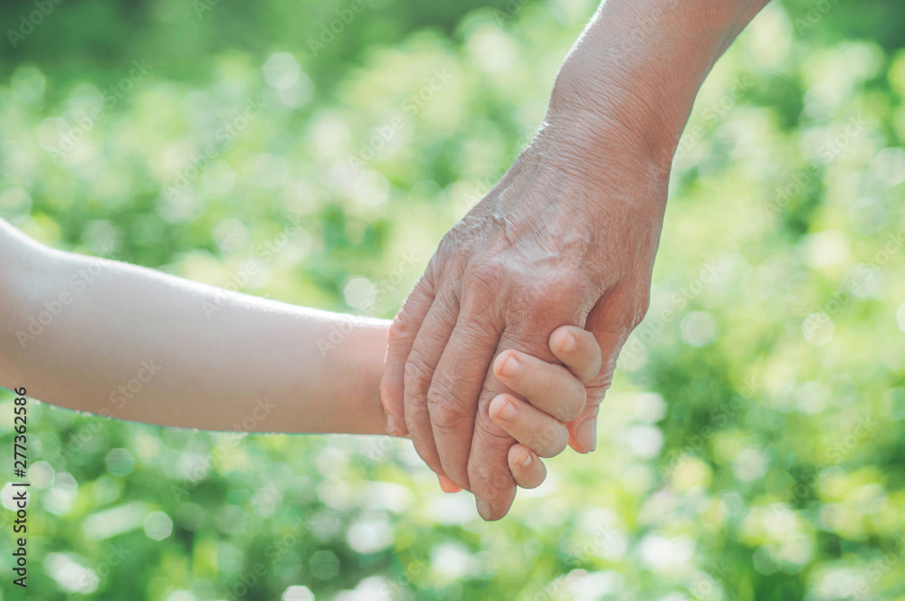 Childs hand and old hand grandmother. Concept idea of love family protecting children and elderly people grandmother friendship togetherness relationship Two generation. Childs hand and old hand grandmother. Concept idea of love family protecting children and elderly people grandmother friendship togetherness relationship Two generation.
