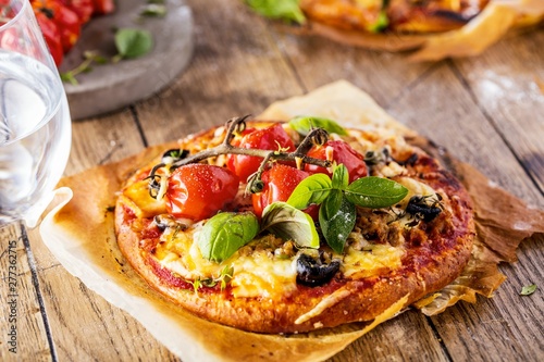 top view of delicious pizza with tomatoes on wooden table