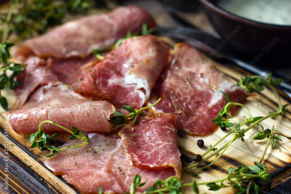 Delicious flavorful ham sliced ​​into strips on a wooden background with spices and fresh thyme. A serving of low-fat succulent farm meat pork. meat product. Food Photography