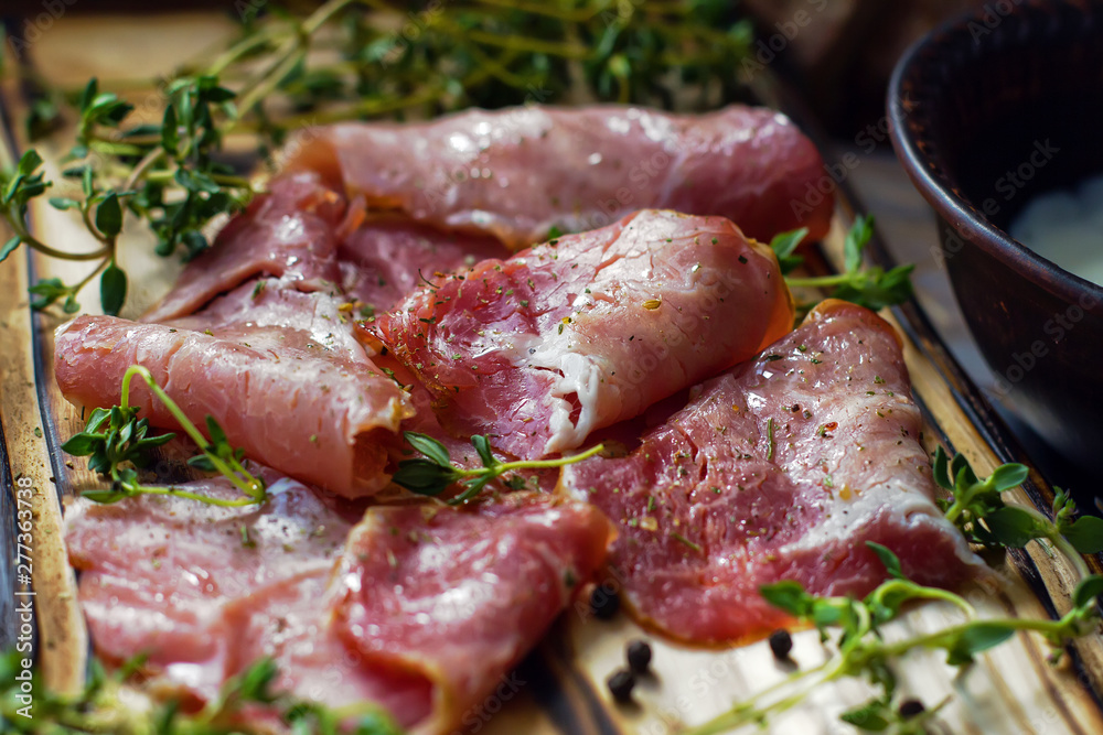 Delicious flavorful ham sliced ​​into strips on a wooden background with spices and fresh thyme. A serving of low-fat succulent farm meat pork. meat product. Food Photography