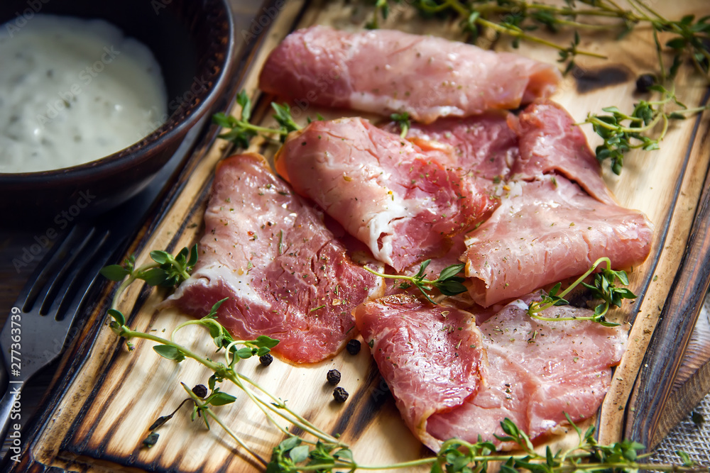 Delicious flavorful ham sliced into strips on a wooden background with spices and fresh thyme. A serving of low-fat succulent farm meat pork. meat product. Food Photography Delicious flavorful ham sliced into strips on a wooden background with spices and fresh thyme. A serving of low-fat succulent farm meat pork. meat product. Food Photography