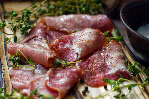 Delicious flavorful ham sliced ​​into strips on a wooden background with spices and fresh thyme. A serving of low-fat succulent farm meat pork. meat product. Food Photography