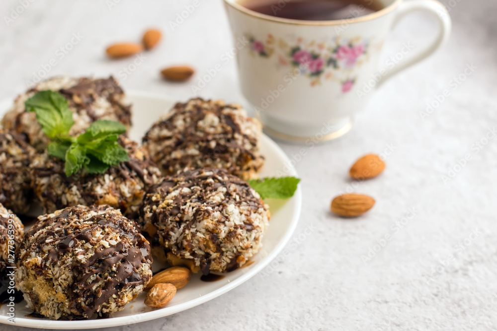 Useful homemade almond cake with coconut flakes on a light background and a cup of tea, copy space Useful homemade almond cake with coconut flakes on a light background and a cup of tea, copy space