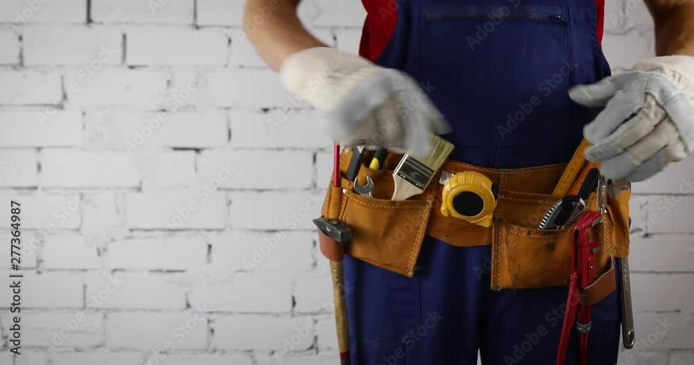 construction worker with tool belt standing on white brick wall background copy space construction worker with tool belt standing on white brick wall background copy space
