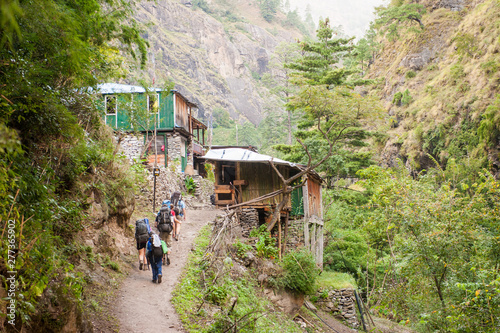 A group of trekkers heading to Lho village on Manaslu circuit with view of Mount Manaslu range (8 156 meters). Himalayas, stone buildings in village, at Manaslu Glacier in Gorkha District in Nepal
