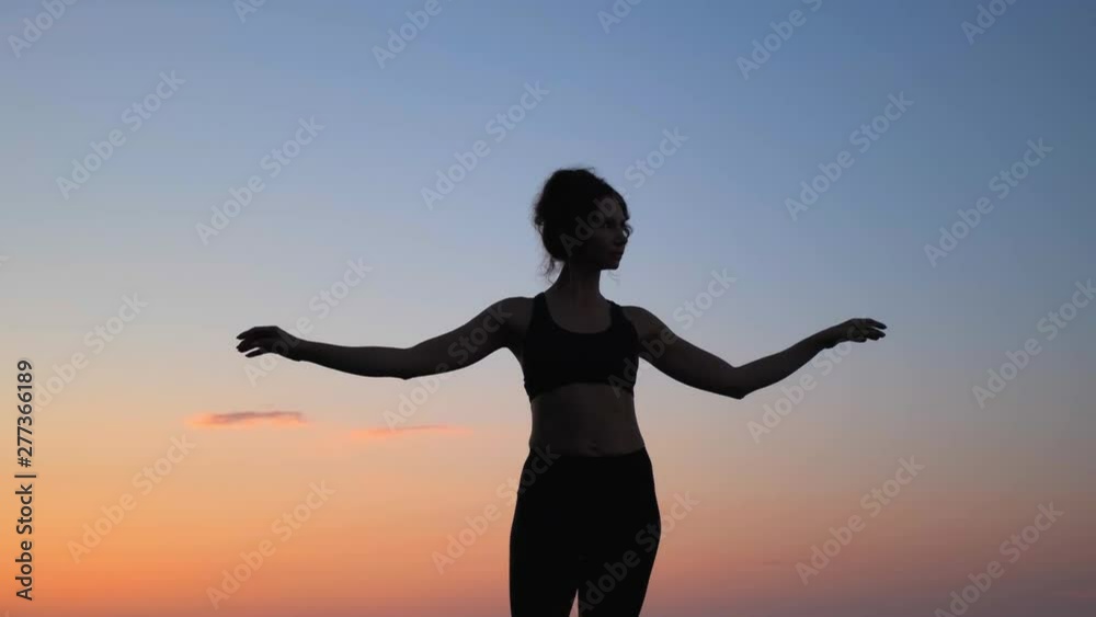 Young skinny woman raises leg doing her yoga morning exercises on early sunrise awesome view slow motion Young skinny woman raises leg doing her yoga morning exercises on early sunrise awesome view slow motion