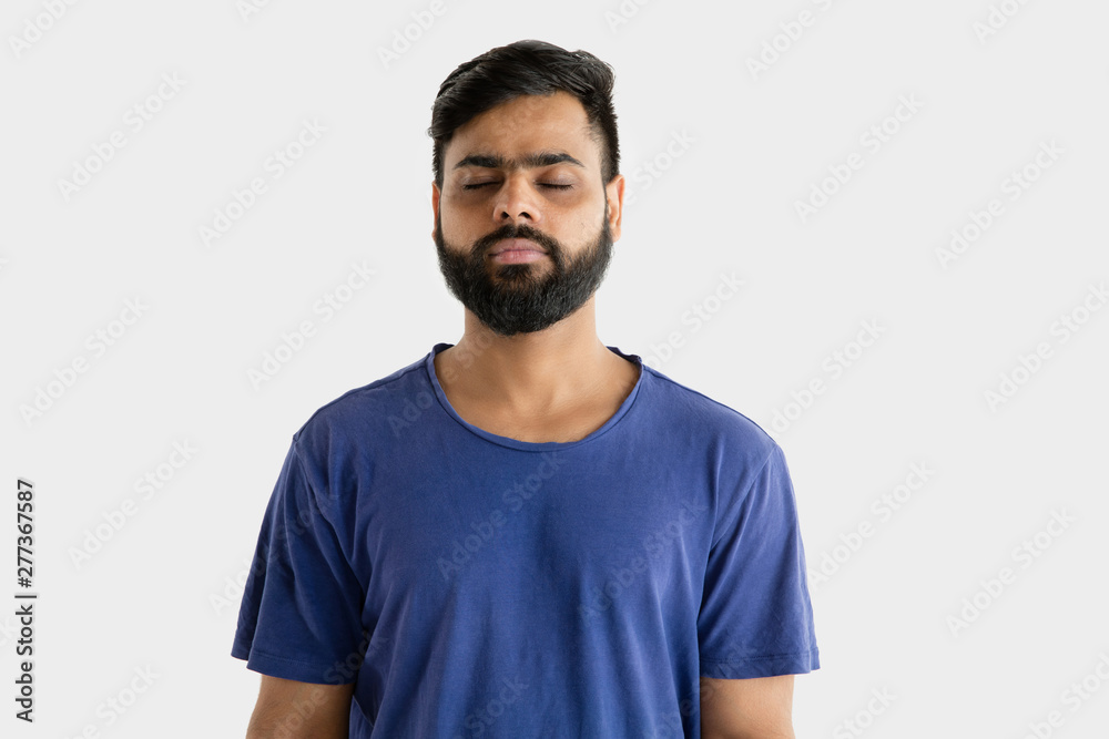 Beautiful male half-length portrait isolated on white studio background. Young emotional hindu man in blue shirt. Facial expression, human emotions, advertising concept. Standing calm with eyes closed