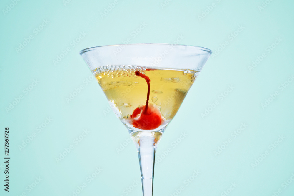 One martini glass, filled with champagne with cherrie and liquid nitrogen, creating steam, isolated on blue background One martini glass, filled with champagne with cherrie and liquid nitrogen, creating steam, isolated on blue background