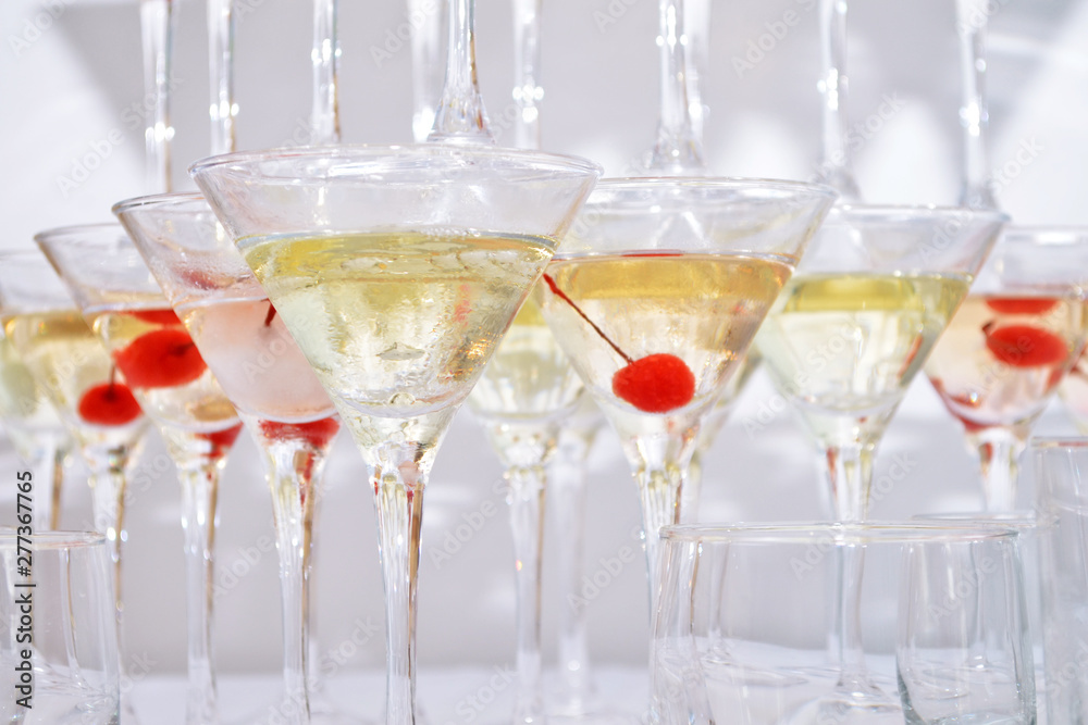 Obraz premium Triangular martini glasses, filled with wine with cherries and liquid nitrogen, creating steam, built in shape pyramid