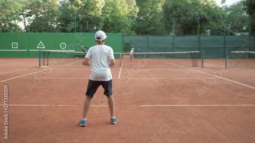 Wallpaper Mural professional tennis, young tennis players boy and girl play sports with help of ball and rackets on red court outdoors Torontodigital.ca