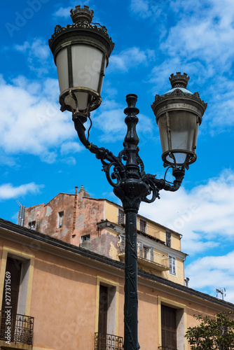 Typical old street light of the corsican Bastia city with colorful buildings on the background during summer day. France 2019.