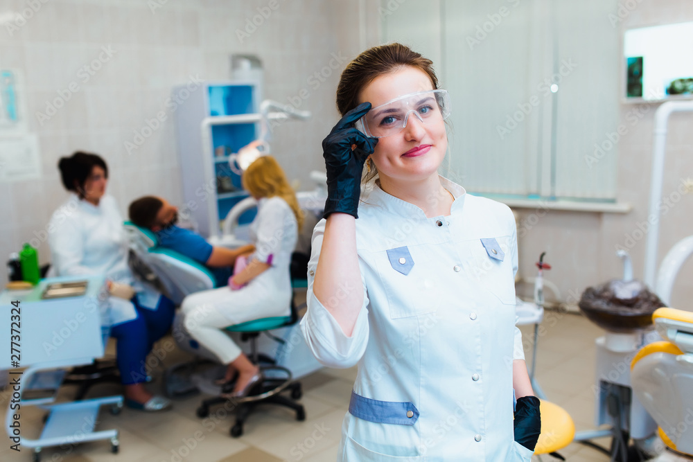 Obraz premium Dental clinic. Portrait of a professional dentist on the background of a working team of doctors. Concept of medical education and medical insurance