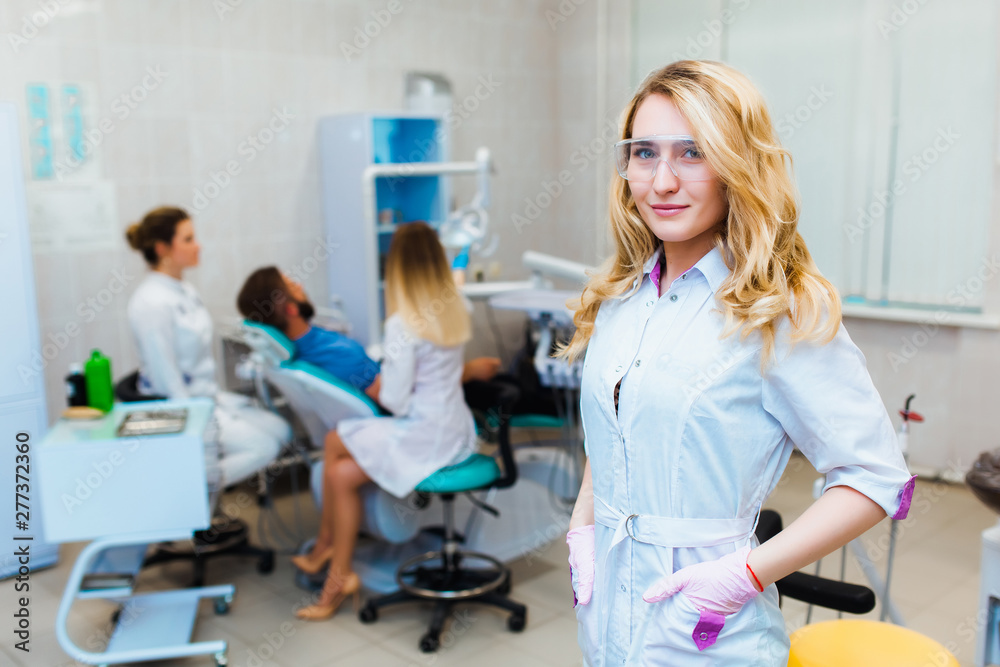Fototapeta premium Dental clinic. Portrait of a professional dentist on the background of a working team of doctors. Concept of medical education and medical insurance