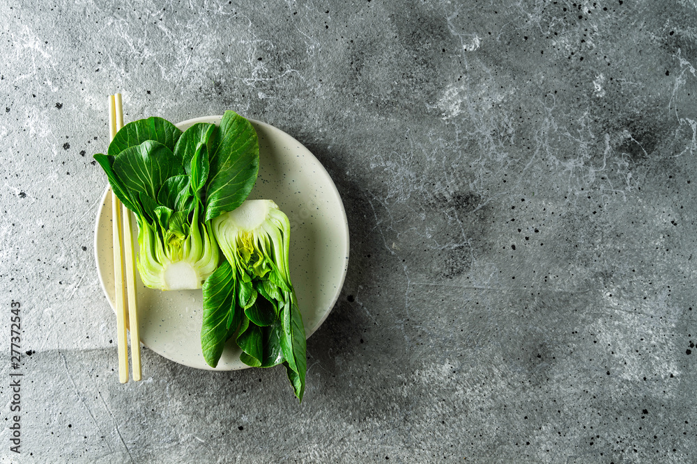 Baby bok choi halves on a plate gray background. Top view, horizontal orientation with copy space - obrazy, fototapety, plakaty 