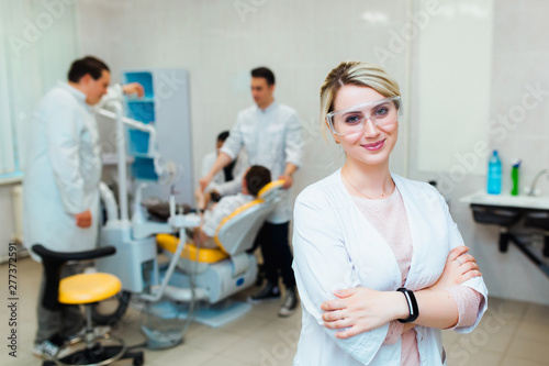 Dental clinic. Portrait of a professional dentist on the background of a working team of doctors. Concept of medical education and medical insurance