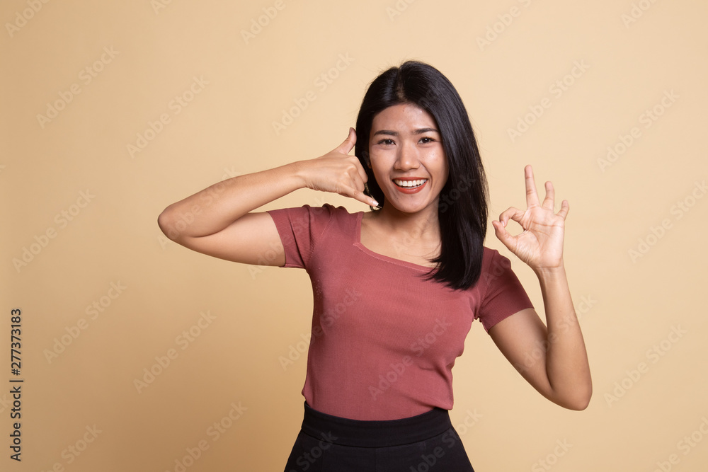 Young Asian woman show with phone gesture and OK sign. Young Asian woman show with phone gesture and OK sign.