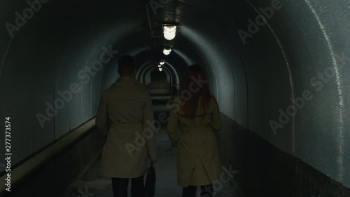 Tilt up rear view shot of businessman and woman going through the tunnel in the evening photo
