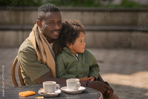 Fotografie african american daughter sitting on the fathers laps at the table in outdoor ca