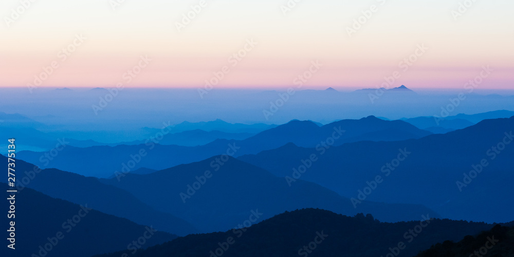 Naklejka premium Poonhill view of mountains around Annapurnas. Warm pink and orange sunrise light over Annapurna mountain range with blue sky and beautiful clouds, Morning on Poon hill in Himalayas, Nepal.