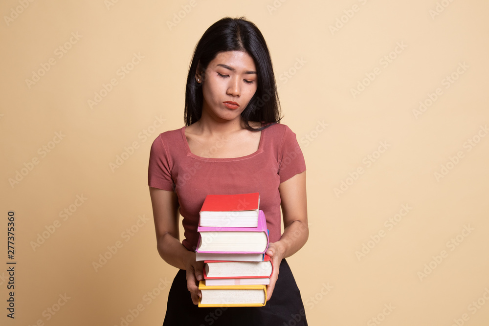 Unhappy young Asian woman studying  with may books.