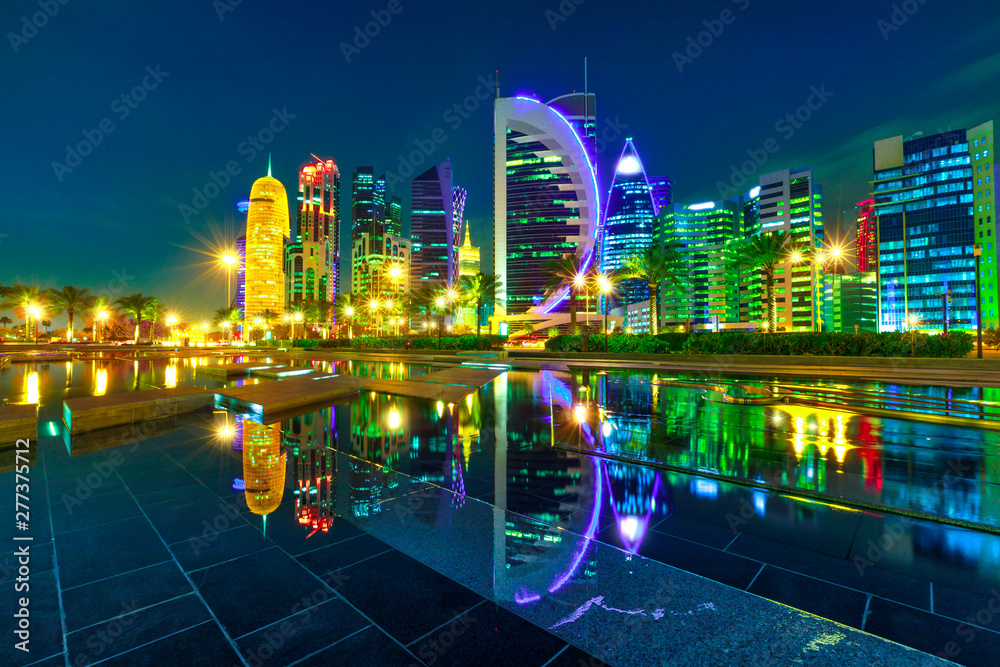 Fototapeta premium The colorful towers of Doha West Bay reflection by night. Evening skyline over the Persian Gulf, Middle East, Doha, Qatar. Night urban scene.