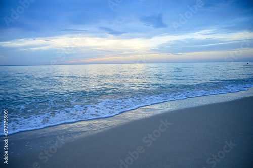 Landscape of sandy beach with soft wave and sunrise sky with cloud